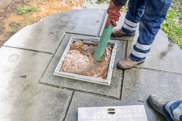 during cesspool pumping, a professional uses a vacuum truck to remove the accumulated waste and sludge from the cesspool